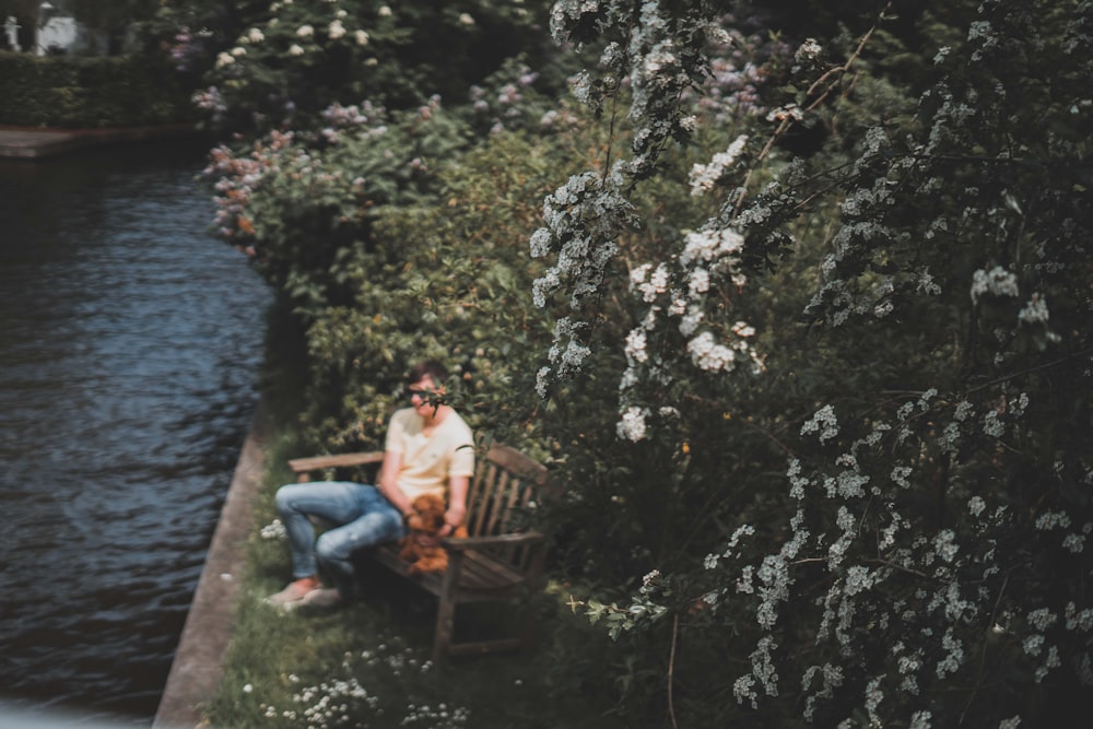 a man sitting on a bench next to a river