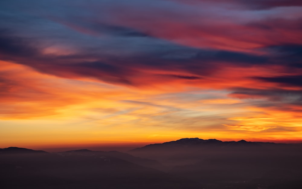 a view of a sunset with a mountain range in the distance