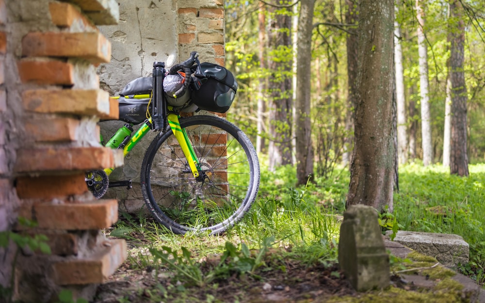 a bike parked next to a brick wall in the woods