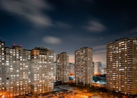 Night view of a city skyline with illuminated high-rise apartments available for rent.