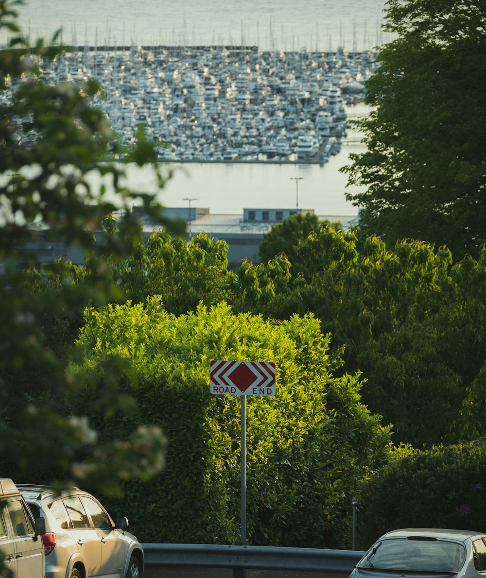 a red and white street sign sitting next to a lush green forest