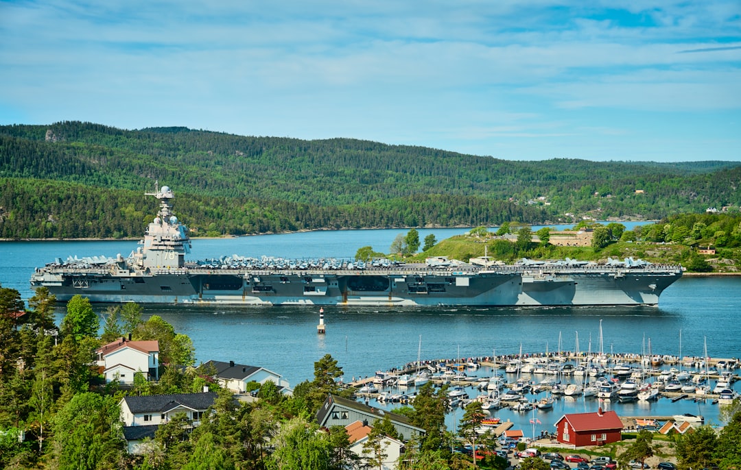 a large navy ship in the water near a marina