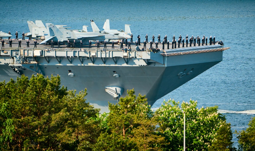 a large navy ship with a bunch of fighter jets on top of it