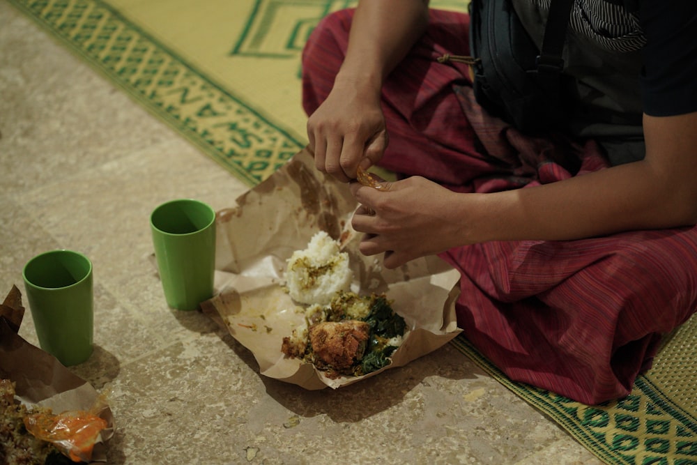 Una mujer sentada en el suelo comiendo comida