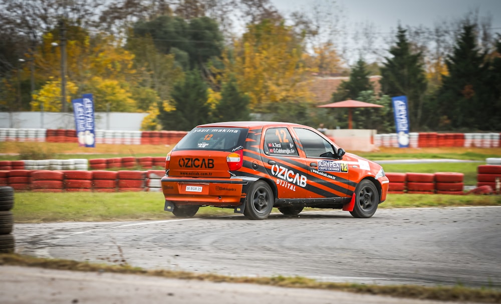 a small orange car driving down a race track