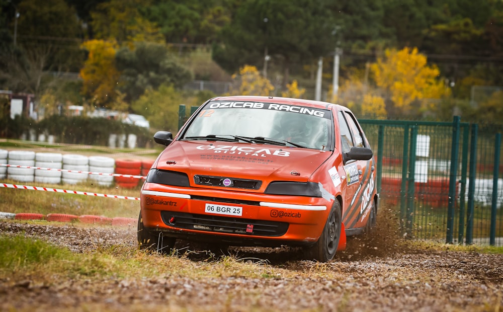 a red car driving down a dirt road