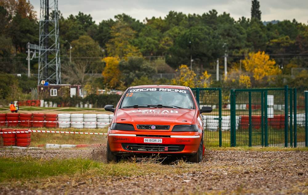 a red car driving down a dirt road