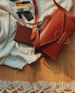 A bright morning scene showing a makeup bag spilling out soft-toned lipsticks and blushes on a light wooden table.