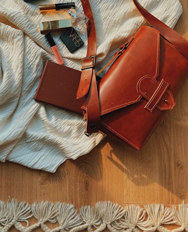 A bright morning scene showing a makeup bag spilling out soft-toned lipsticks and blushes on a light wooden table.
