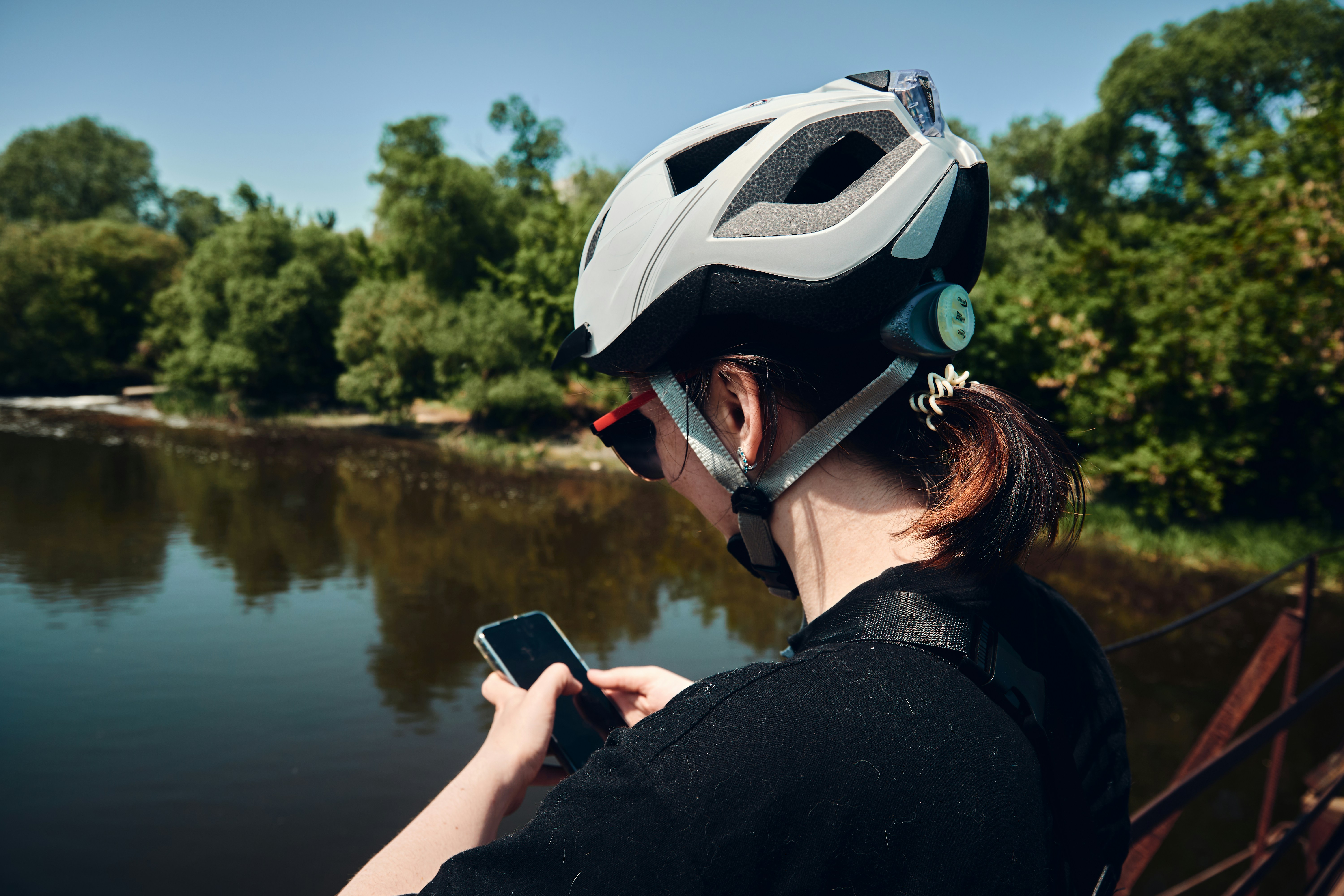 Una mujer con casco mirando su teléfono celular