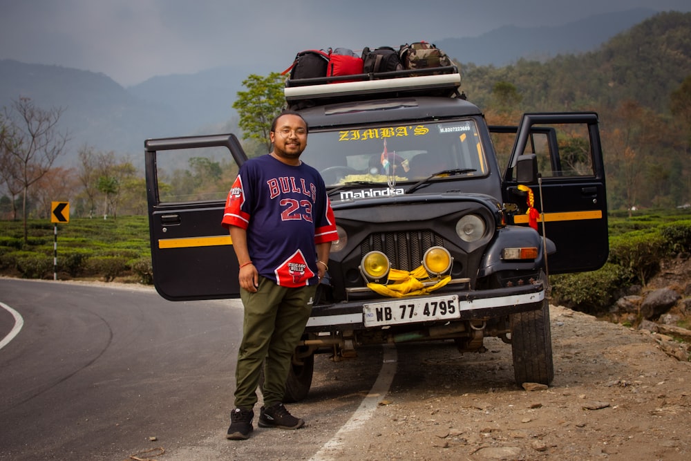 a man standing next to a jeep on a road