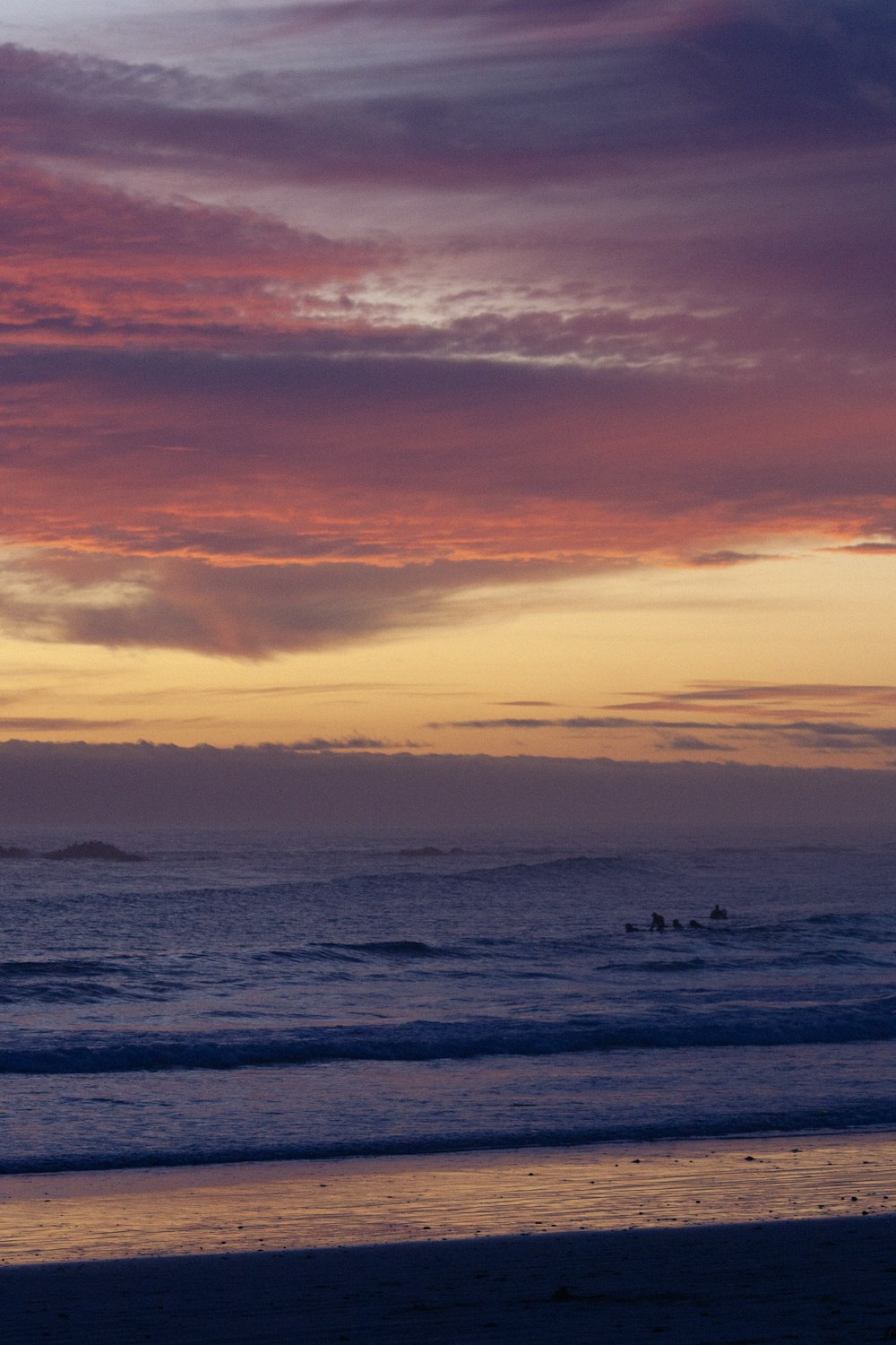 a sunset view of the ocean with a surfer in the distance