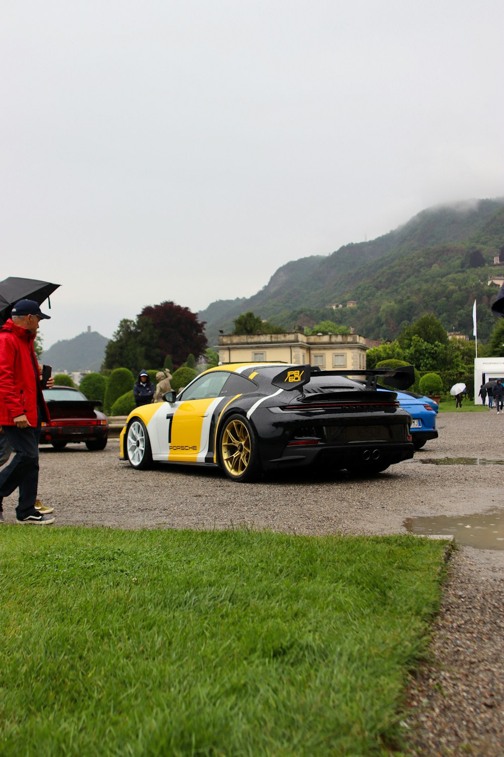 a man with an umbrella standing next to a sports car