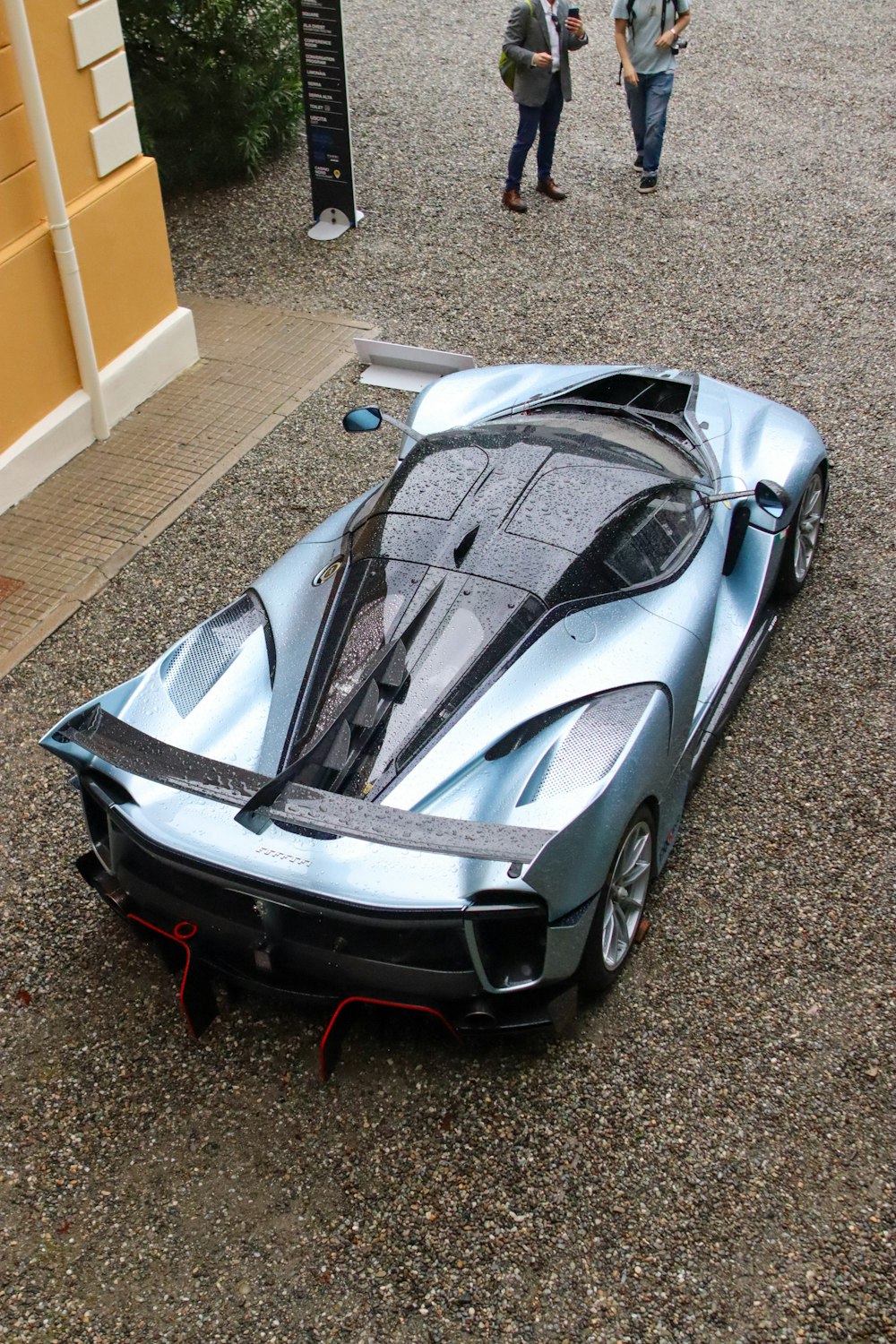 a silver sports car parked on top of a gravel road