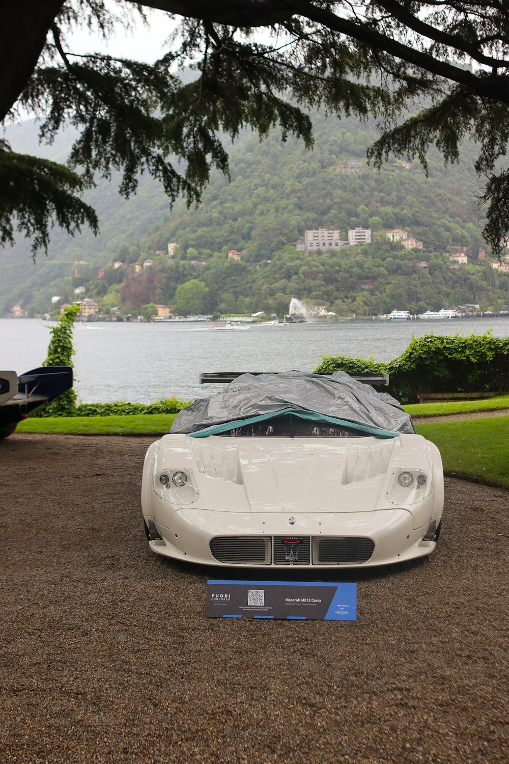 a white sports car parked in front of a lake