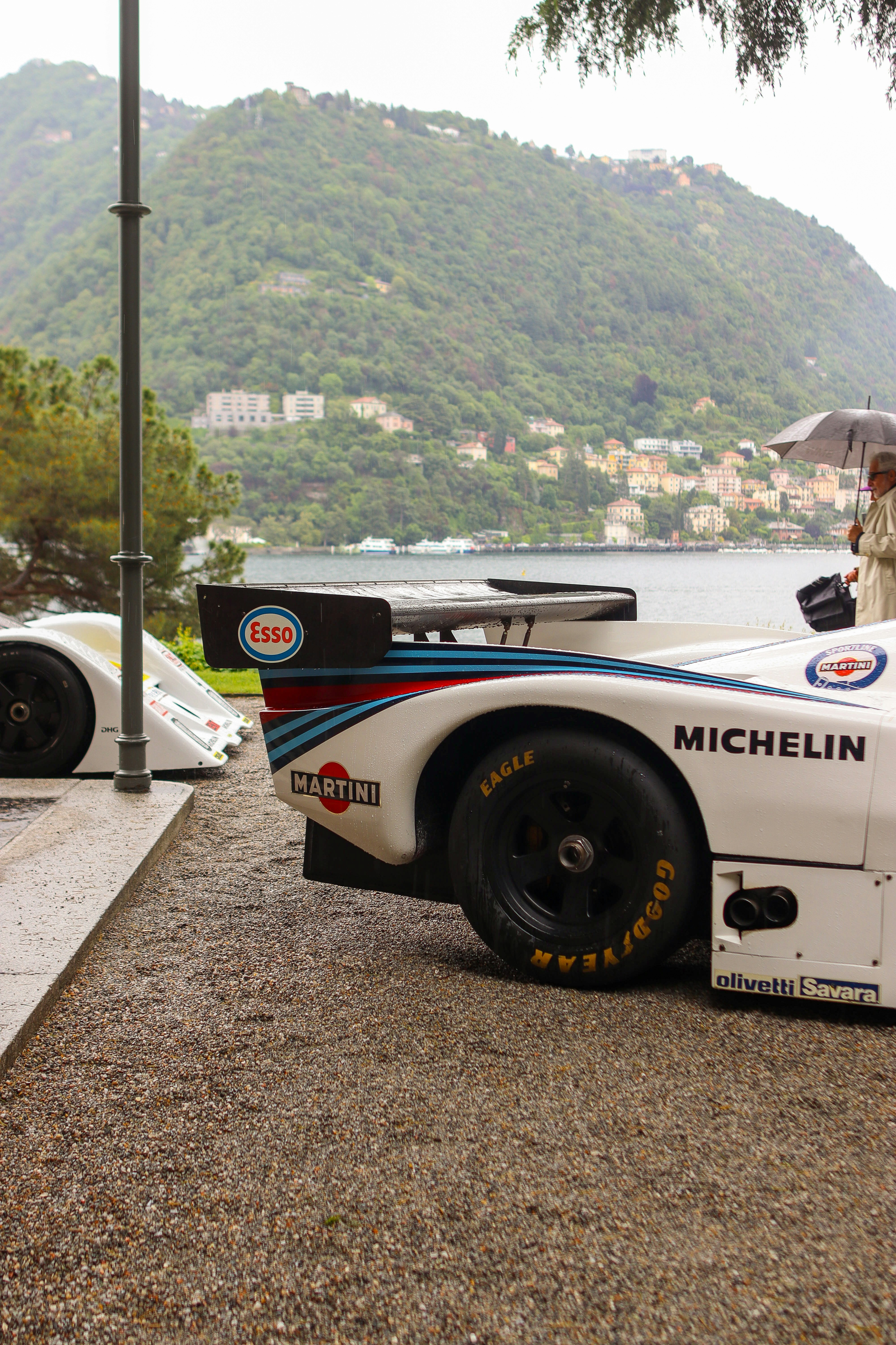 a man holding an umbrella standing next to a race car