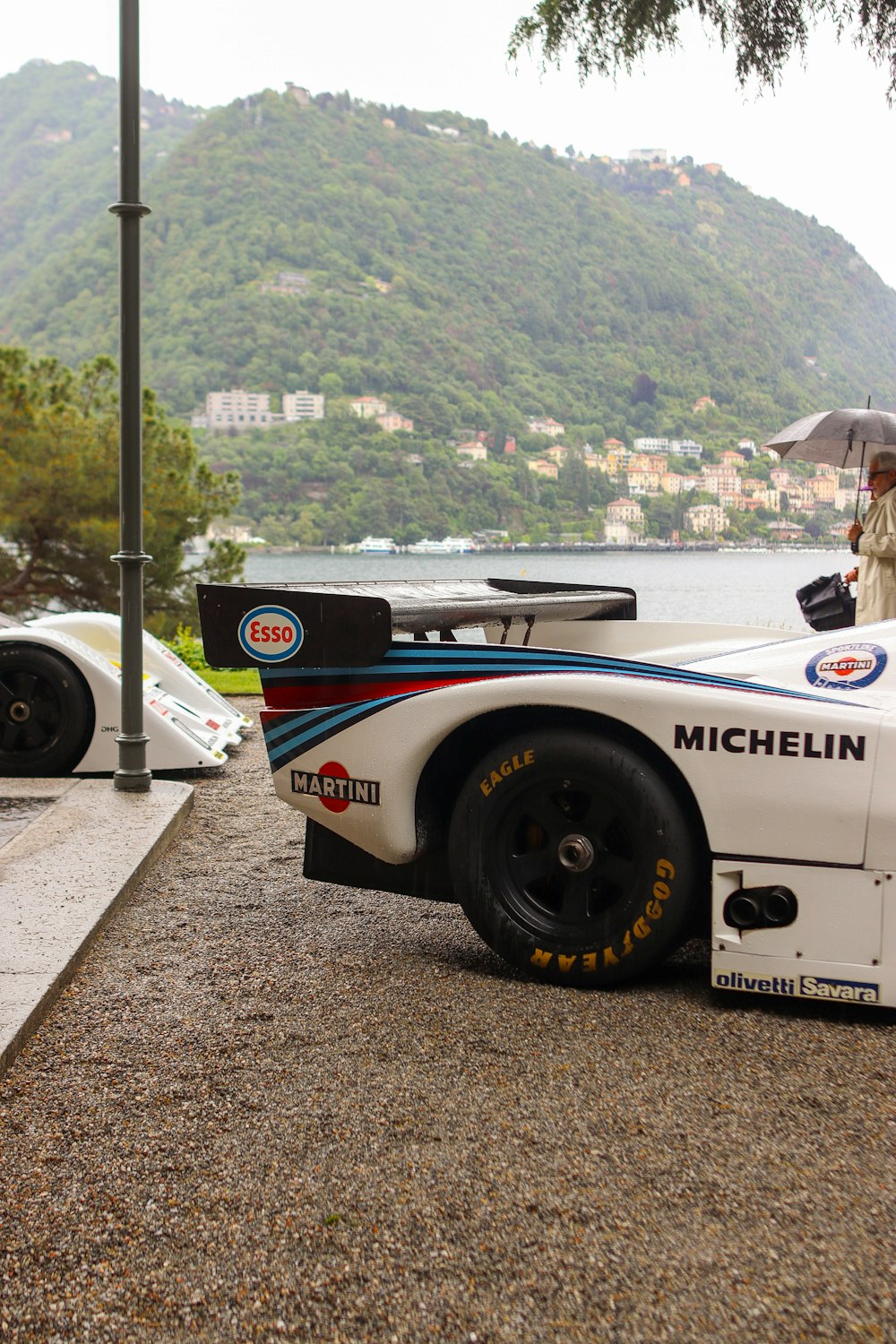 a man holding an umbrella standing next to a race car