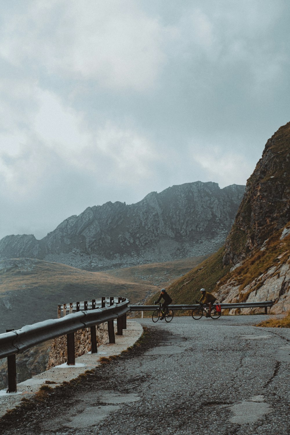 Un hombre montando en bicicleta por una carretera junto a una montaña