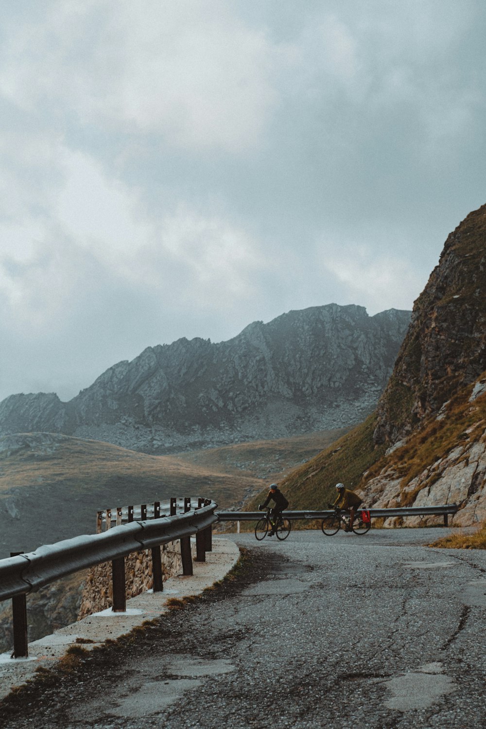 a man riding a bike down a road next to a mountain
