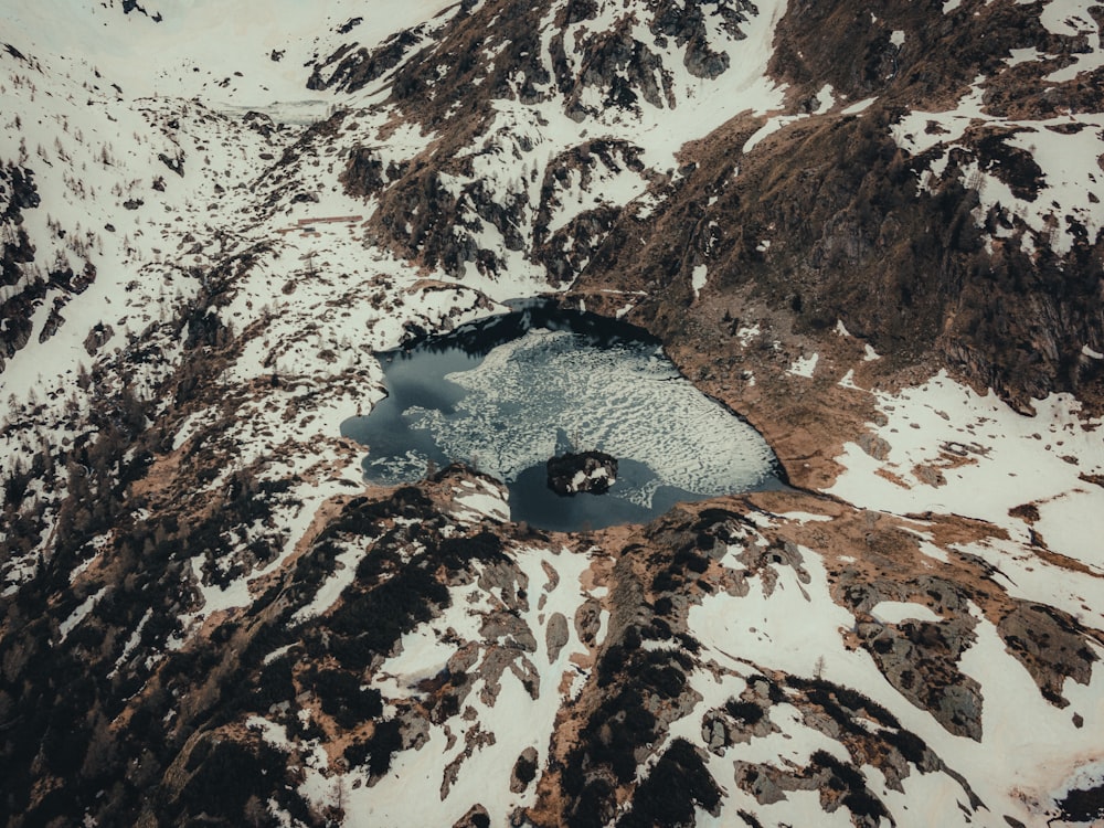 an aerial view of a mountain lake surrounded by snow
