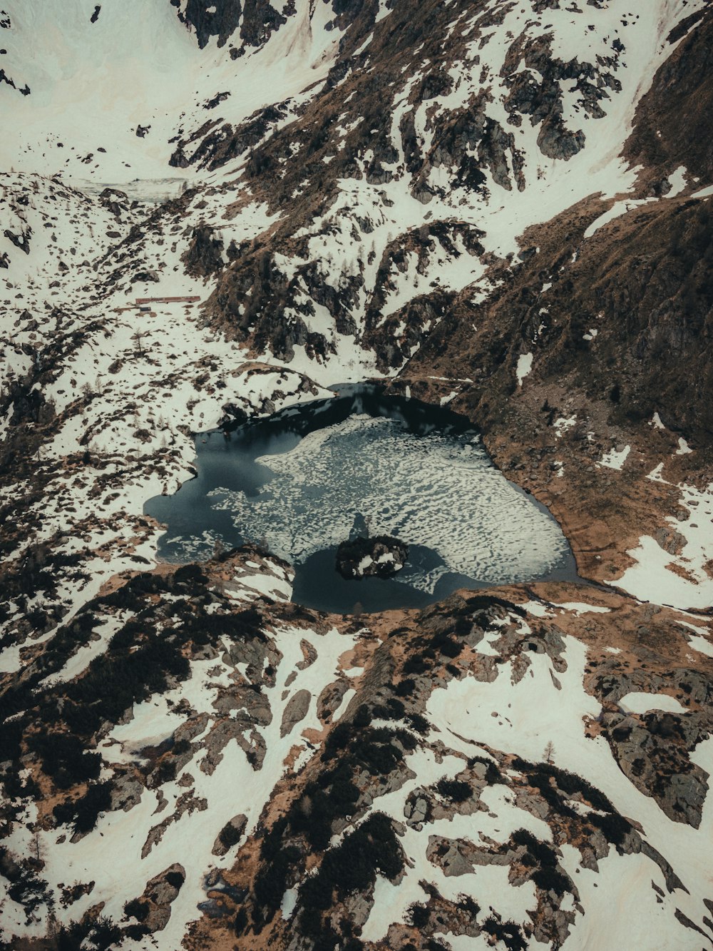 an aerial view of a mountain lake surrounded by snow