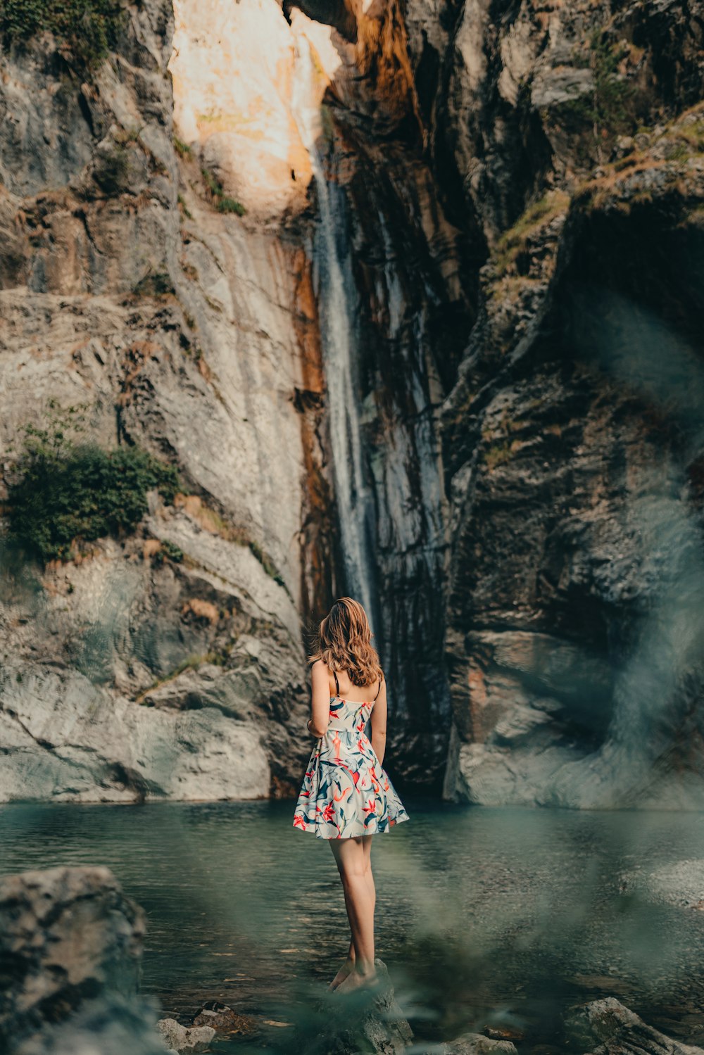 a woman standing in front of a waterfall