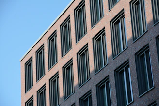 A construction crew laying bricks on a modern bank building under a clear blue sky.
