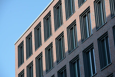 A construction crew laying bricks on a modern bank building under a clear blue sky.