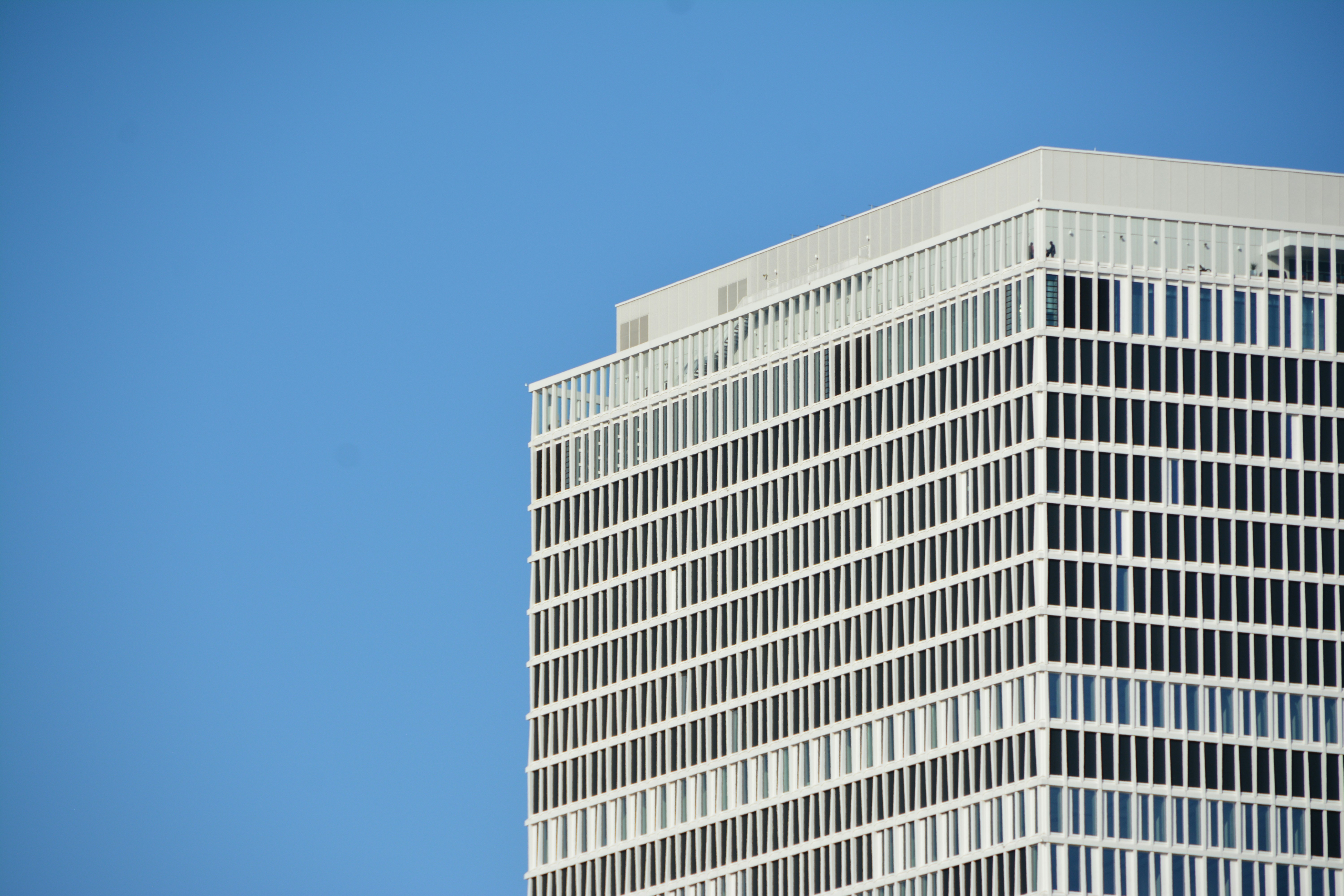a plane flying in the sky over a tall building