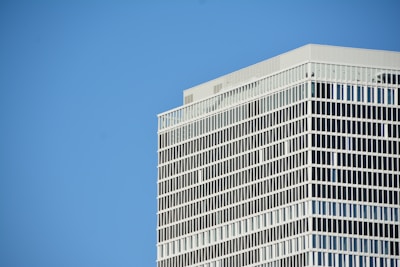 a plane flying in the sky over a tall building