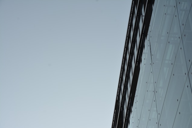 A sleek, modern building under construction showcasing steel framework and glass panels against a clear sky.
