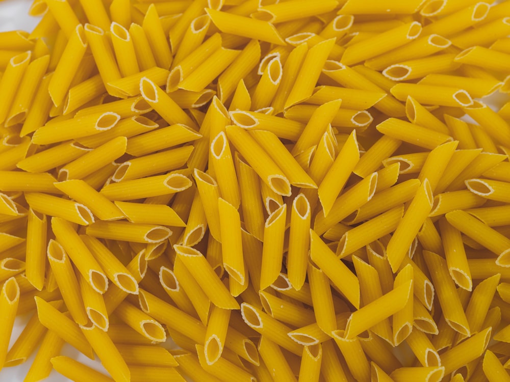 a pile of yellow pasta noodles on a white surface