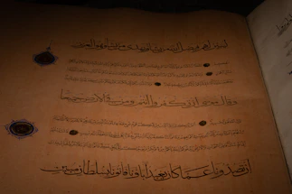 A vintage Ottoman manuscript with intricate gold and burgundy patterns surrounding a handwritten letter.