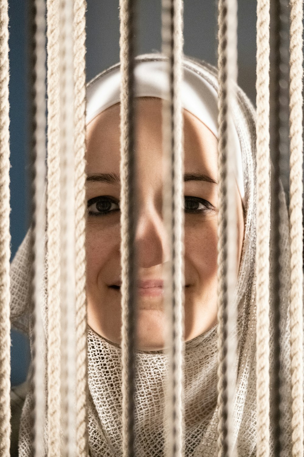 a woman is smiling behind the bars of a cage