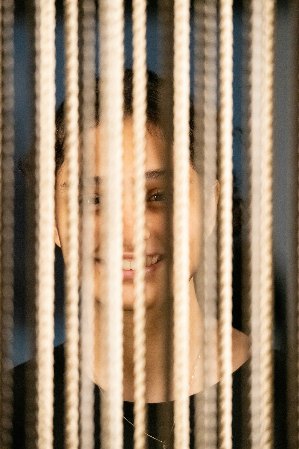 a young girl looking through the bars of a window