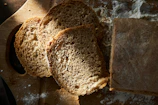 Artisanal bread and fresh herbs on a wooden board, captured in natural light with a matte forest green backdrop.