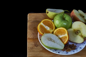 A plate of fresh, colorful fruits arranged beautifully on a wooden table.