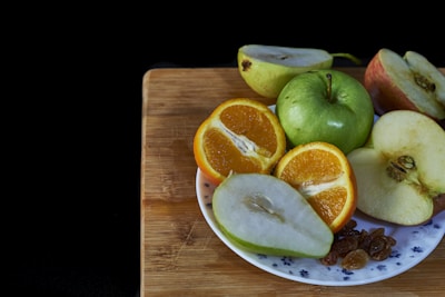 A small plate showcasing an assortment of safe fruits including apple slices without seeds, papaya, and berries.