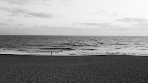 An athlete running along a rugged coastline with waves crashing nearby.