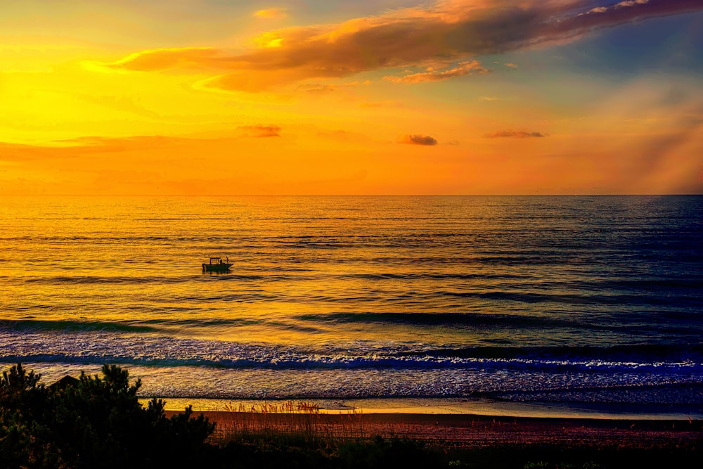 a boat is out in the ocean at sunset