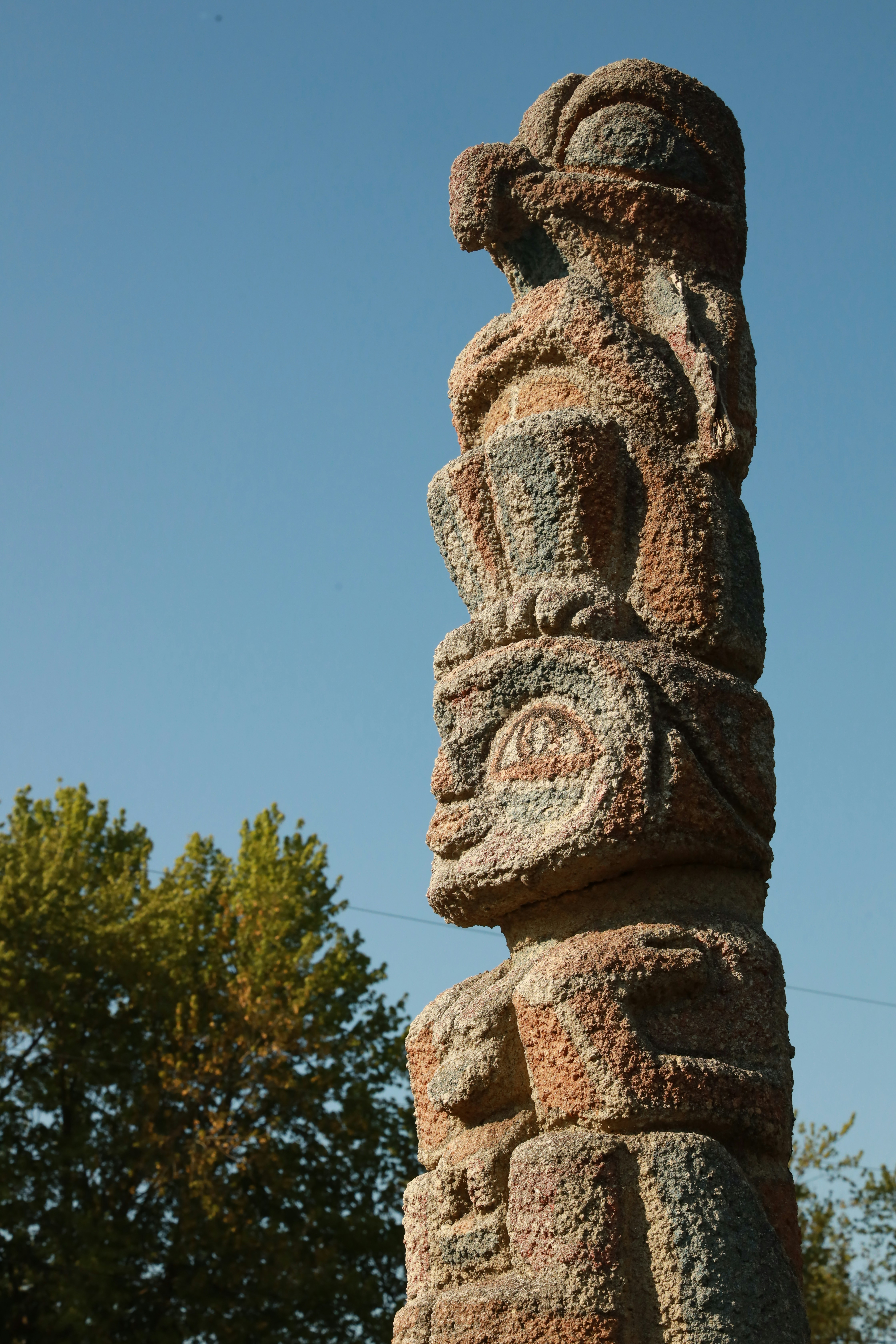 A statue made of rocks with a tree in the background photo Free Emblem Image on Unsplash