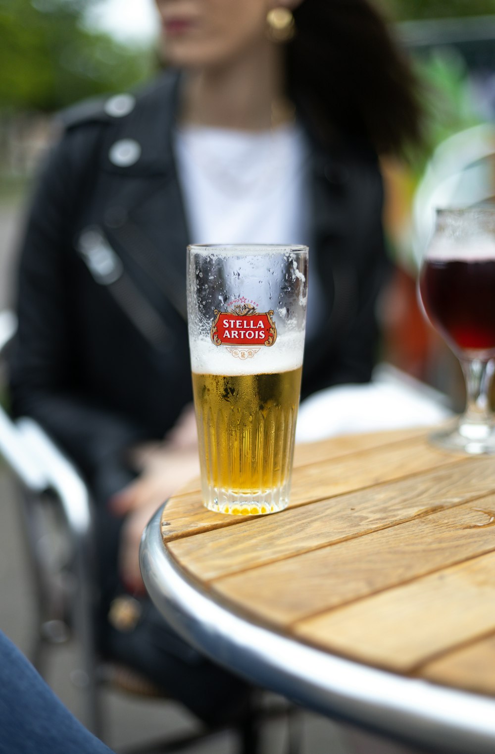 a glass of beer sitting on top of a wooden table