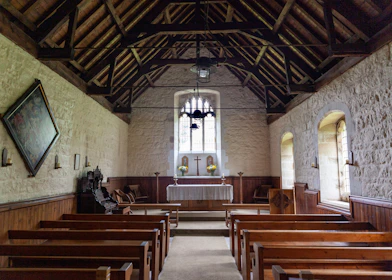 Interior of a small rustic chapel with wooden pews and soft natural light.