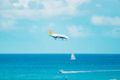 Bob piloting a helicopter above the sparkling ocean, with the catamaran visible below.