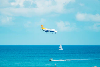 Bob piloting a helicopter above the sparkling ocean, with the catamaran visible below.