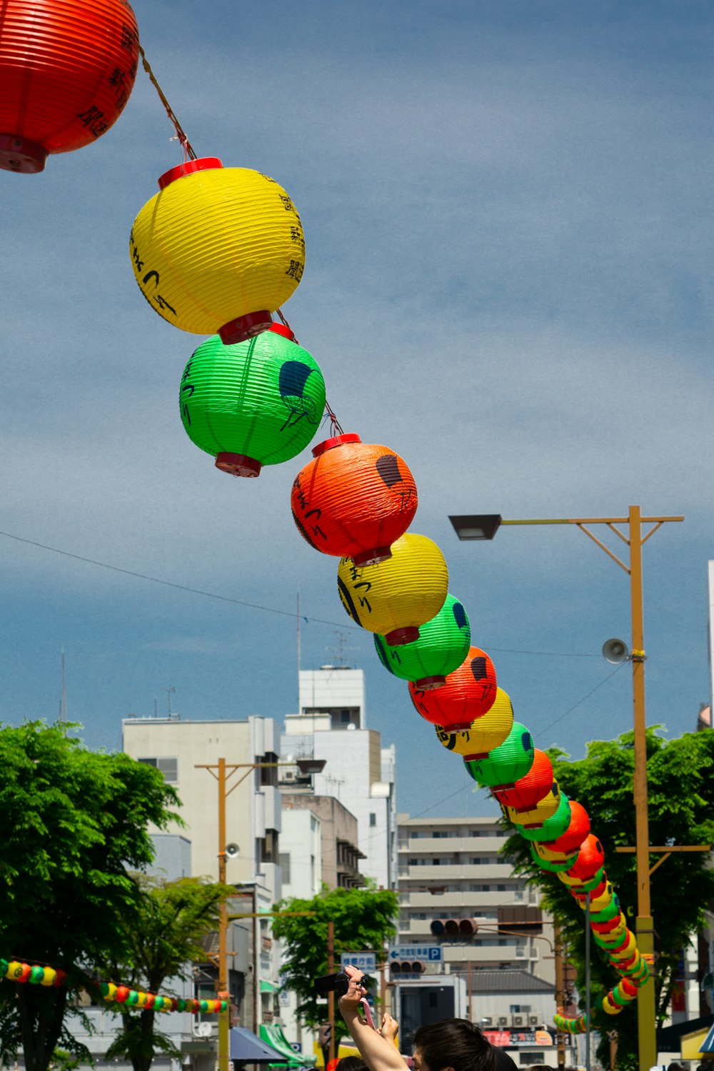 a woman taking a picture of a long line of paper lanterns