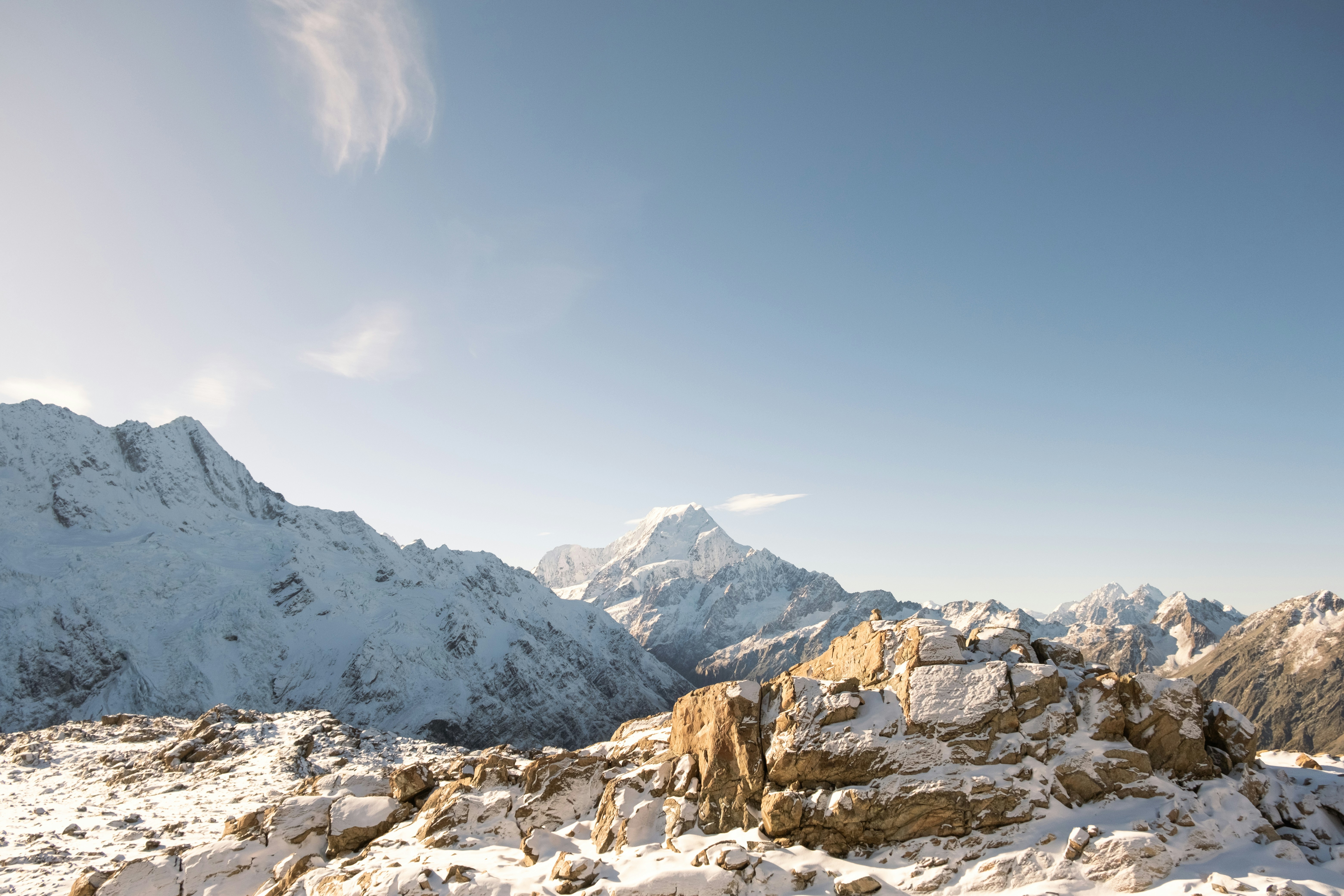 a mountain range covered in snow under a blue sky, 