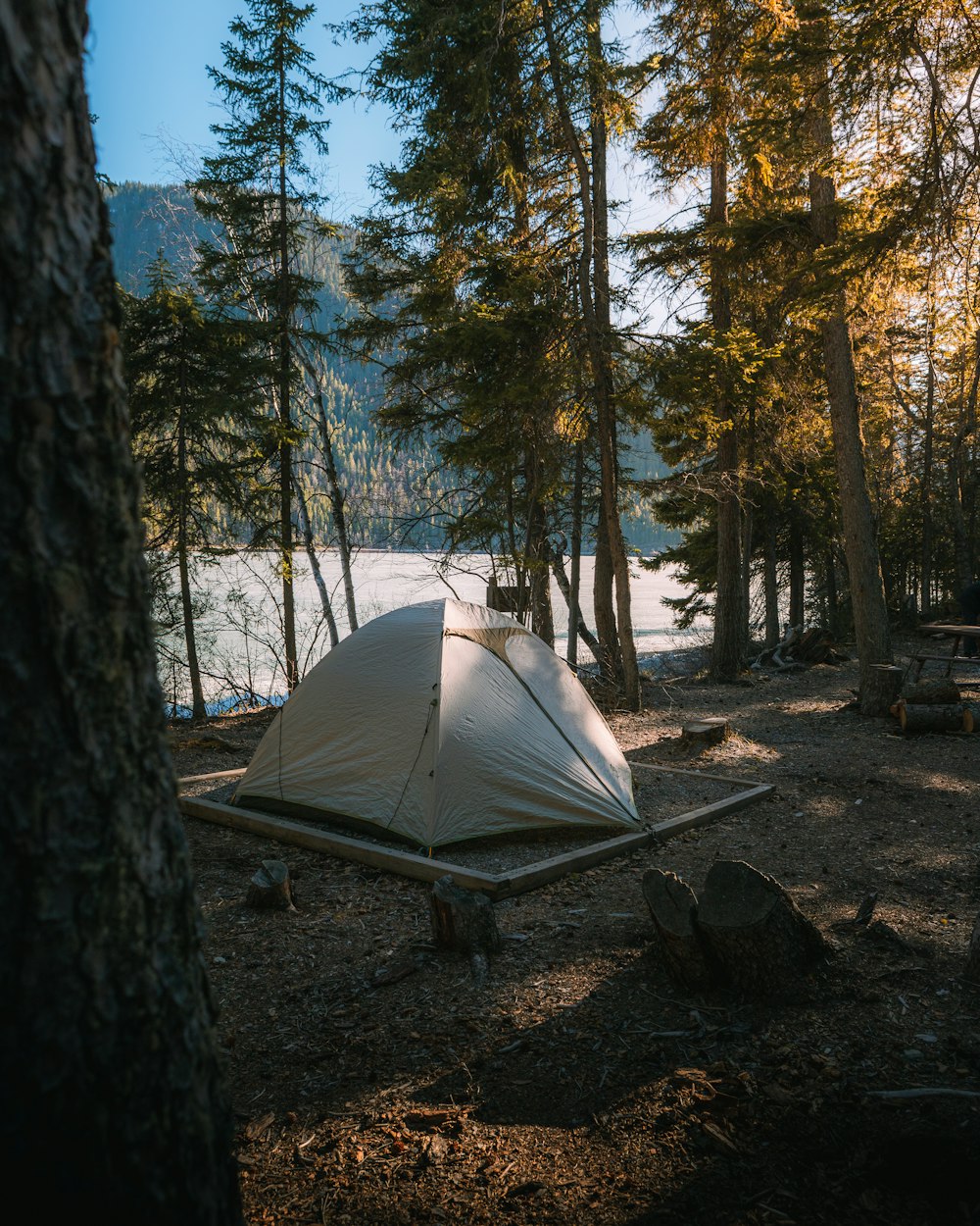 a tent pitched up in the woods next to a lake