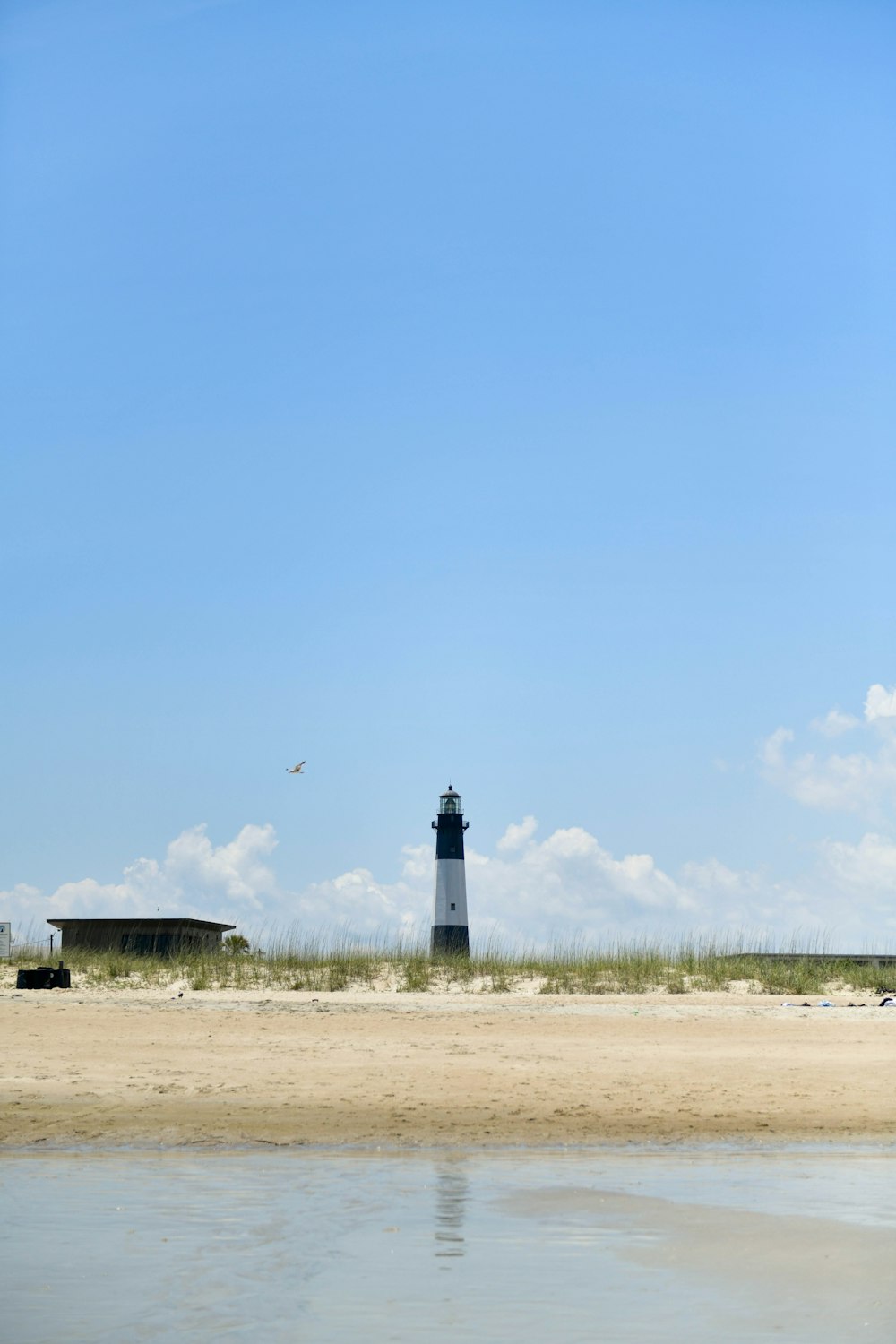 ein leuchtturm an einem strand mit einem blauen himmel im hintergrund