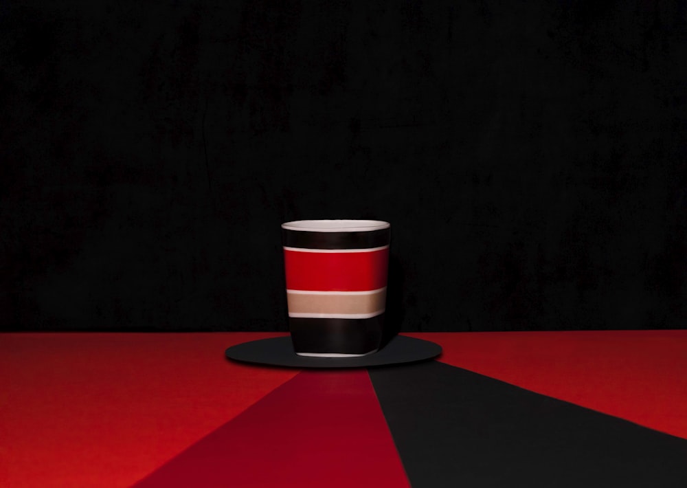 a red and black cup sitting on top of a black plate